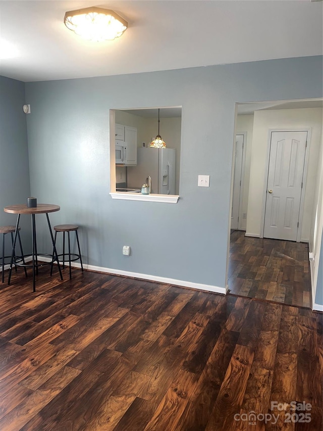 unfurnished room with dark wood finished floors and baseboards