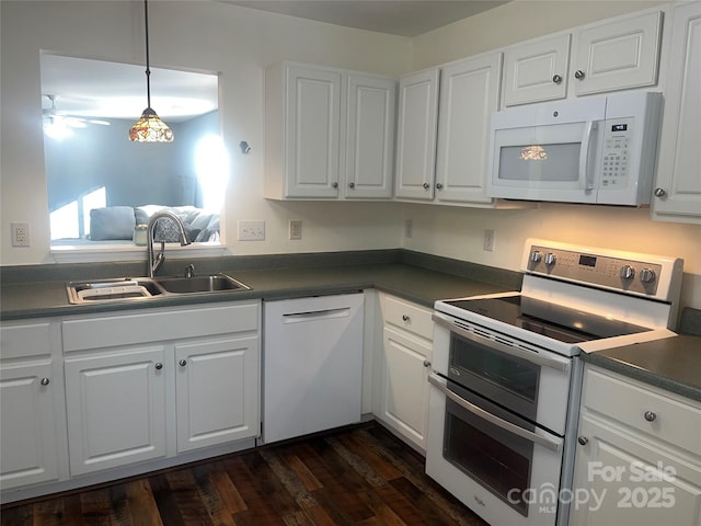 kitchen with dark countertops, white appliances, white cabinetry, and a sink