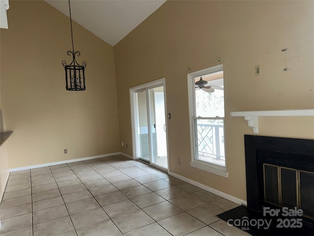 interior space featuring light tile patterned floors, a fireplace with flush hearth, ceiling fan, high vaulted ceiling, and baseboards