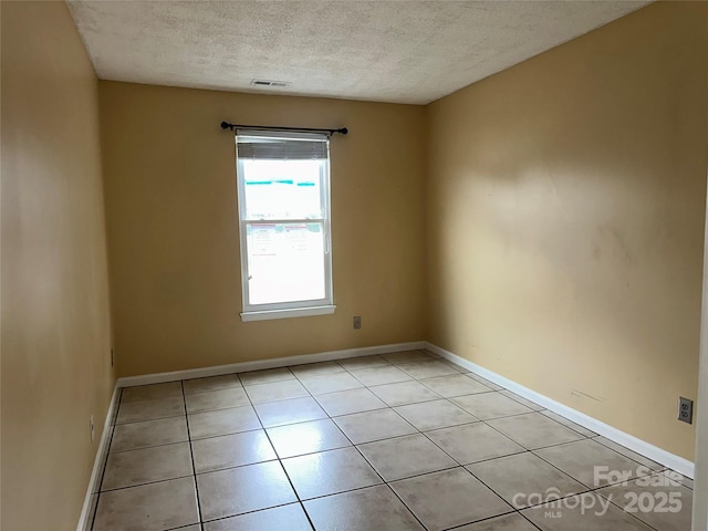 unfurnished room featuring light tile patterned floors, a textured ceiling, visible vents, and baseboards