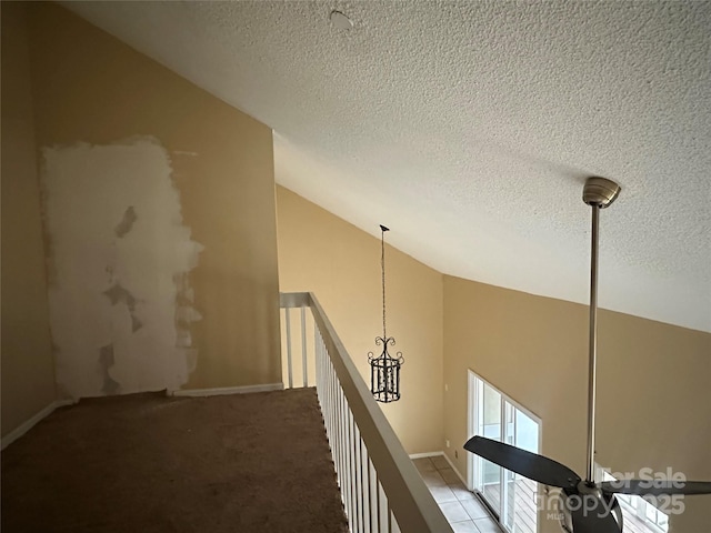 hall featuring vaulted ceiling, a textured ceiling, and carpet flooring