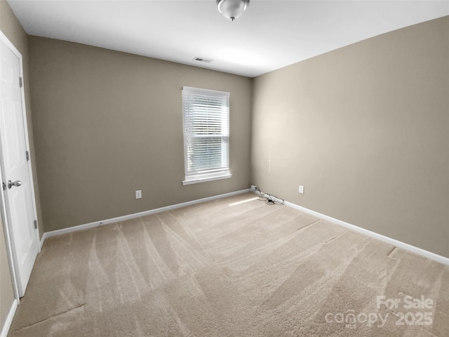 spare room with baseboards, visible vents, and light colored carpet