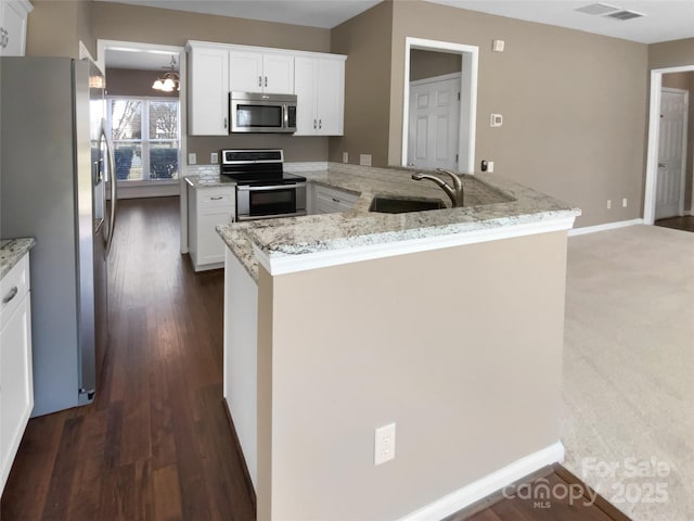 kitchen featuring stainless steel appliances, a sink, visible vents, white cabinets, and light stone countertops