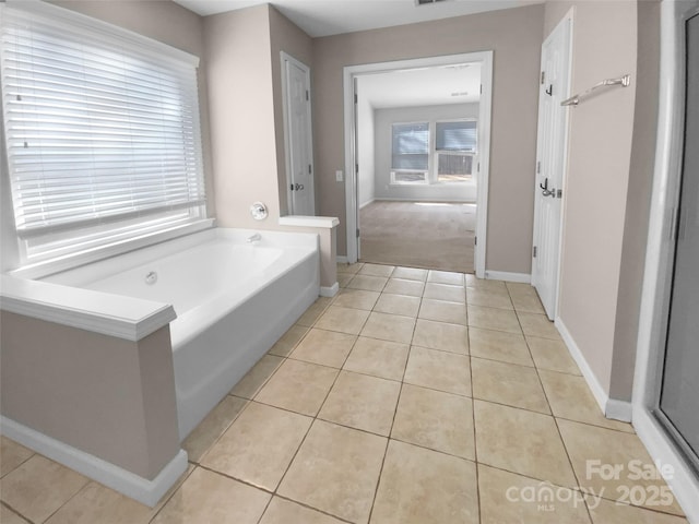 full bathroom with a garden tub, tile patterned flooring, and baseboards