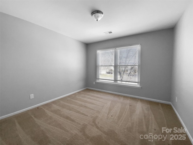 carpeted spare room featuring visible vents and baseboards