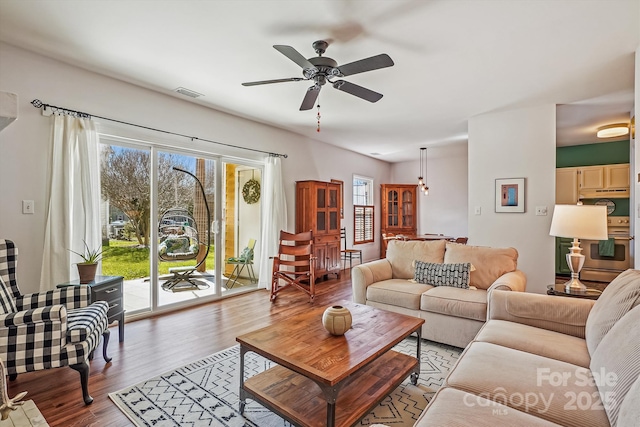 living room with wood finished floors, visible vents, and a ceiling fan