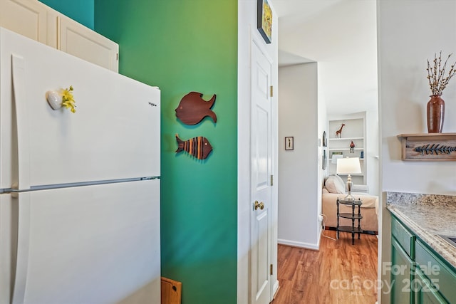 kitchen featuring light wood-style floors, freestanding refrigerator, white cabinets, and light countertops