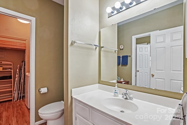 bathroom with toilet, wood finished floors, and vanity