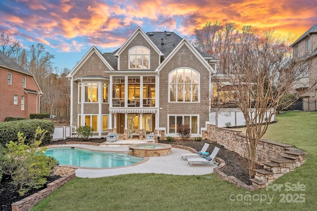 back of house with a patio area, a balcony, a yard, and a pool with connected hot tub