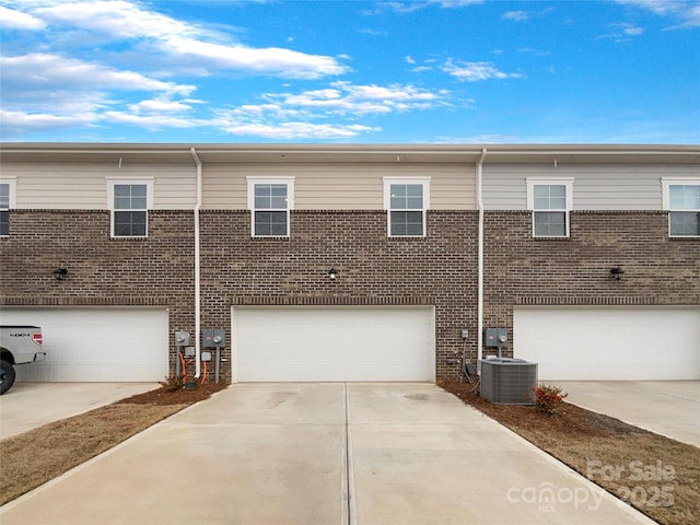 exterior space with a garage, brick siding, driveway, and central AC unit