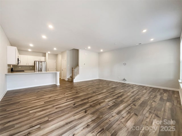 unfurnished living room with recessed lighting, dark wood finished floors, and baseboards