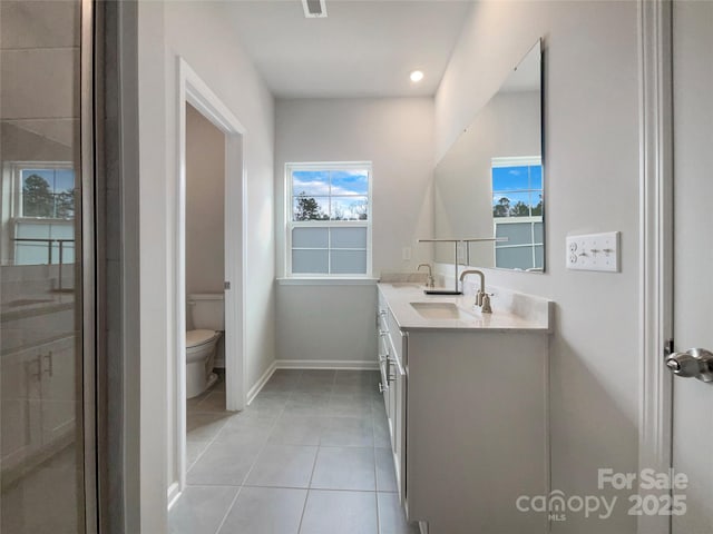 bathroom with toilet, a sink, baseboards, tile patterned floors, and double vanity