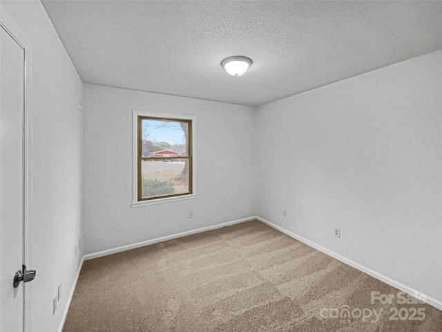 unfurnished room featuring carpet, a textured ceiling, and baseboards