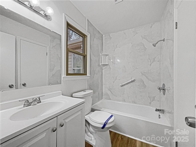 bathroom with toilet, washtub / shower combination, wood finished floors, and vanity