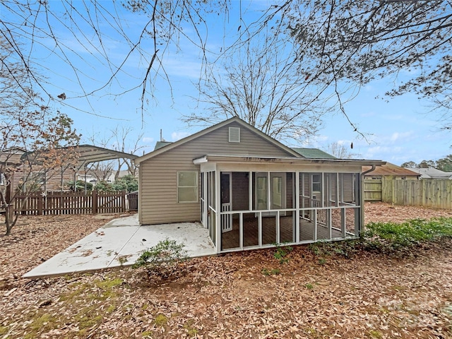 rear view of property featuring a sunroom, a patio area, and fence