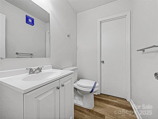 bathroom featuring toilet, wood finished floors, and vanity