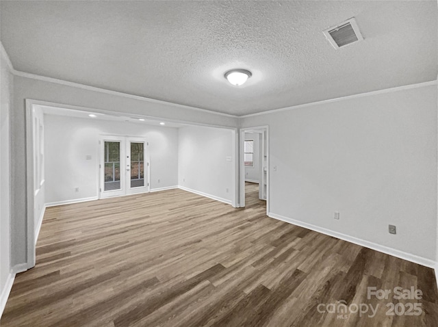 unfurnished room with visible vents, crown molding, a textured ceiling, and wood finished floors