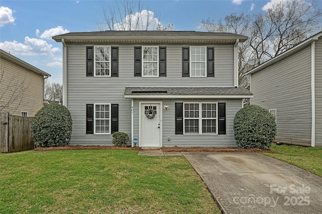 traditional home featuring a front yard, fence, and a shingled roof