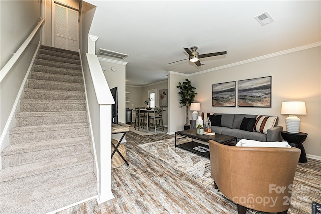 living area featuring visible vents, crown molding, stairs, and ceiling fan