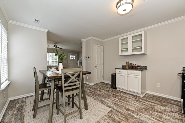 dining space with crown molding, wood finished floors, visible vents, and baseboards