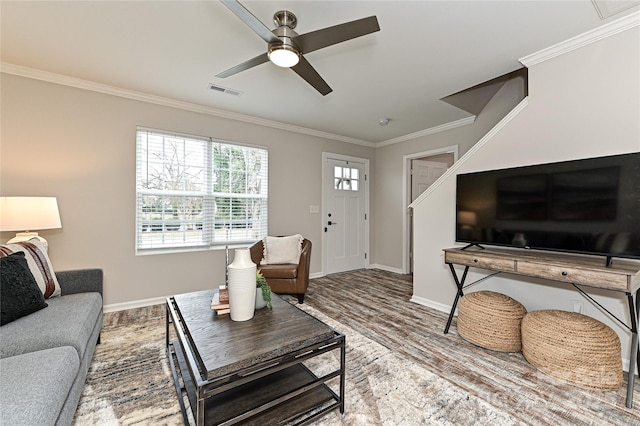 living area featuring visible vents, crown molding, baseboards, and wood finished floors