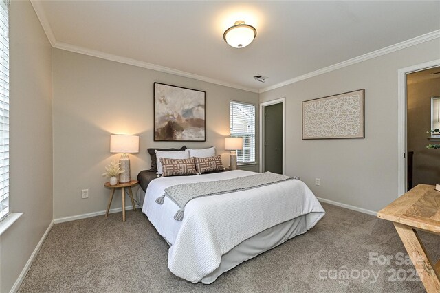 carpeted bedroom featuring visible vents, crown molding, and baseboards