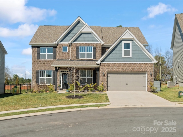 craftsman house with brick siding, fence, concrete driveway, a front yard, and central AC unit