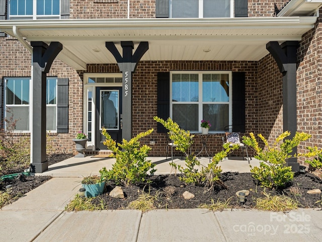 doorway to property featuring brick siding and covered porch