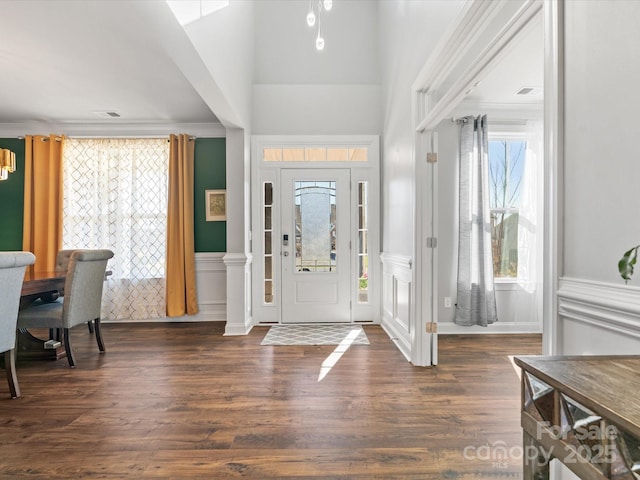 entrance foyer with a wainscoted wall, dark wood-type flooring, and ornamental molding