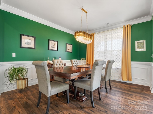 dining area with wainscoting, dark wood-style floors, crown molding, and a chandelier