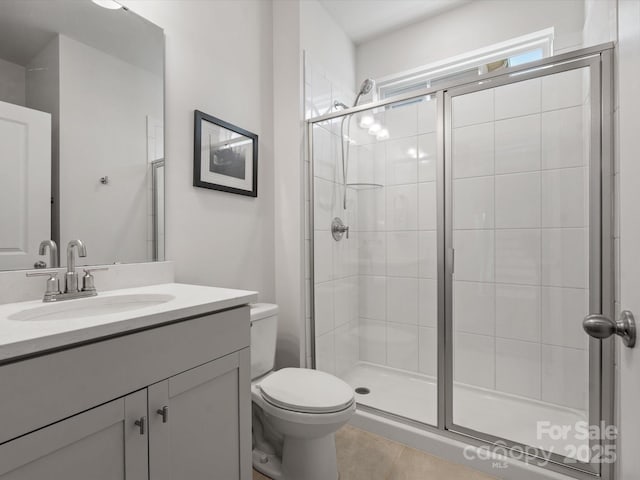 bathroom featuring vanity, a shower stall, toilet, and tile patterned flooring