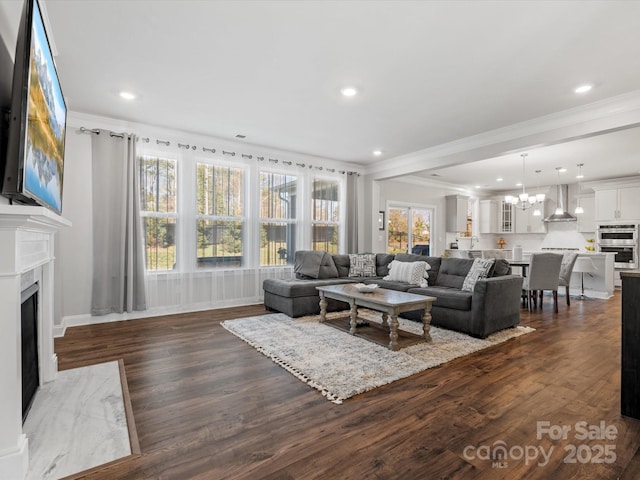 living room with a fireplace, a chandelier, dark wood finished floors, and ornamental molding