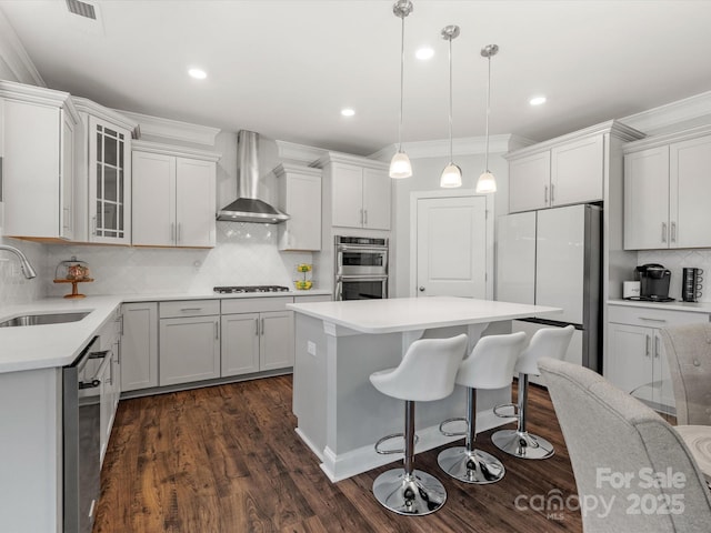 kitchen with a sink, gas cooktop, freestanding refrigerator, double oven, and wall chimney exhaust hood