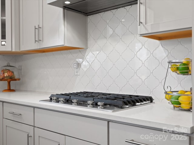 kitchen featuring white cabinetry, stainless steel gas stovetop, light countertops, and custom range hood