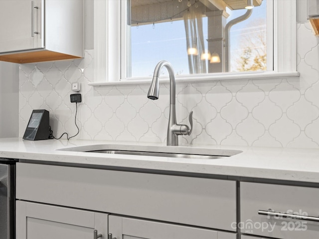 kitchen featuring a wealth of natural light, white cabinetry, light stone counters, and a sink