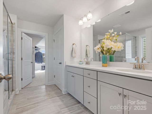 full bathroom with double vanity, visible vents, a stall shower, and a sink