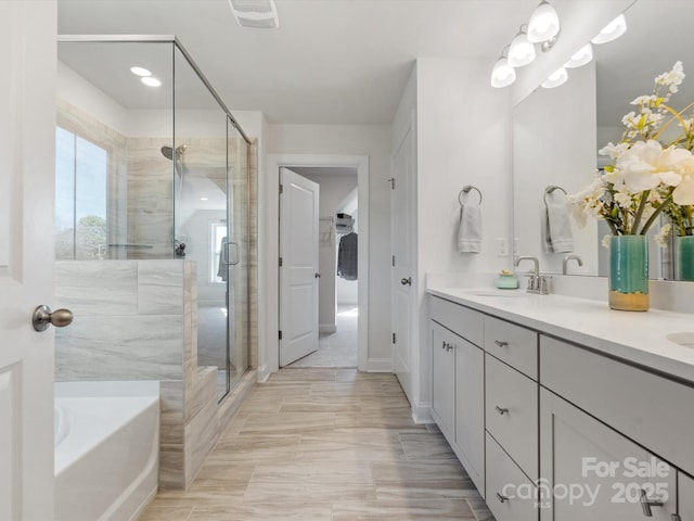 bathroom with visible vents, a garden tub, double vanity, a stall shower, and a sink