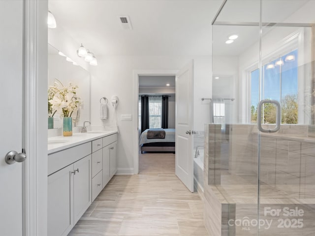 ensuite bathroom with visible vents, an enclosed shower, a sink, ensuite bath, and double vanity