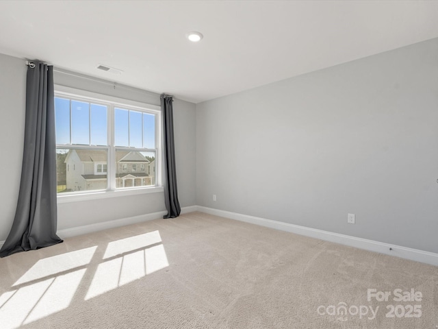 spare room featuring visible vents, light colored carpet, and baseboards