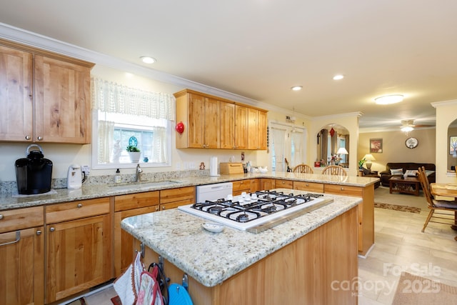 kitchen featuring white appliances, a kitchen island, ornamental molding, a peninsula, and a sink