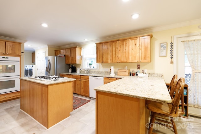 kitchen featuring washer and dryer, white appliances, crown molding, and a peninsula