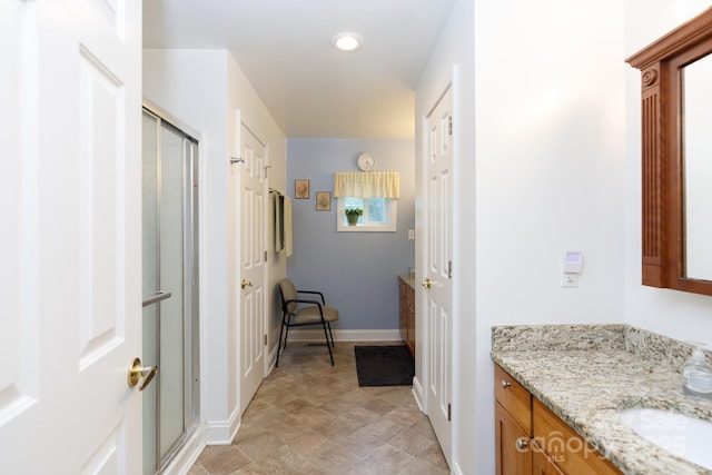 bathroom with baseboards, vanity, and a shower stall