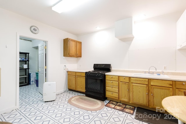 kitchen featuring black gas stove, brown cabinets, light countertops, and a sink