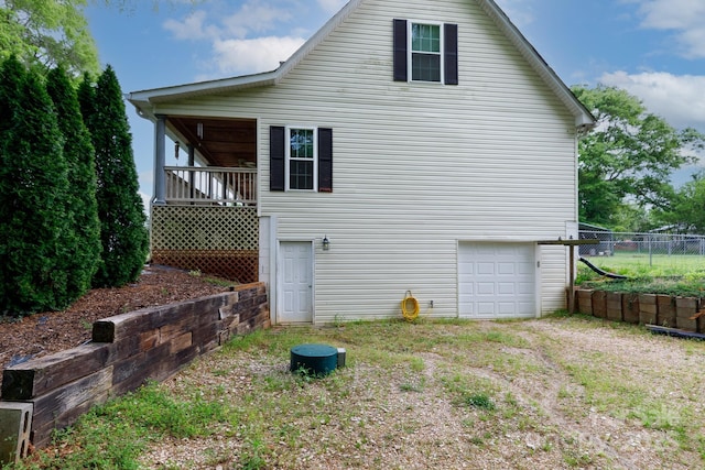 rear view of property with driveway, an attached garage, and fence