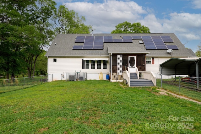 rear view of house with central AC, a yard, a fenced backyard, and solar panels