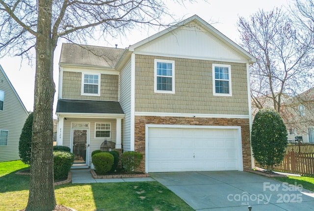 view of front facade with driveway, stone siding, a garage, and fence