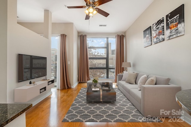 living area with light wood finished floors, visible vents, and a ceiling fan