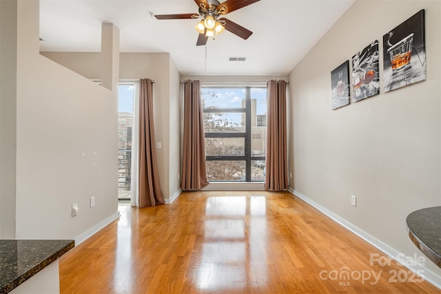 unfurnished dining area with visible vents, baseboards, light wood-style floors, and ceiling fan