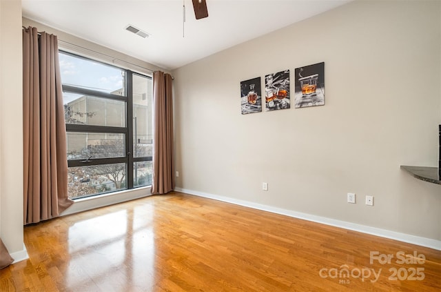 spare room with visible vents, light wood-style flooring, a ceiling fan, and baseboards