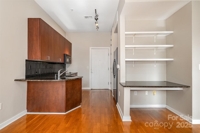 kitchen featuring visible vents, backsplash, black microwave, dark stone countertops, and wood finished floors